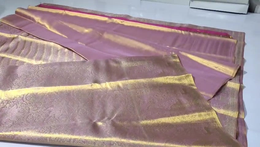 Neatly folded baby pink Kanchipuram handloom tissue silk saree displaying the rich pallu and shimmering metallic finish.