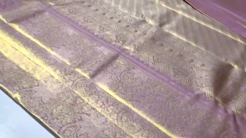 Neatly folded baby pink Kanchipuram handloom tissue silk saree displaying the rich pallu and shimmering metallic finish.