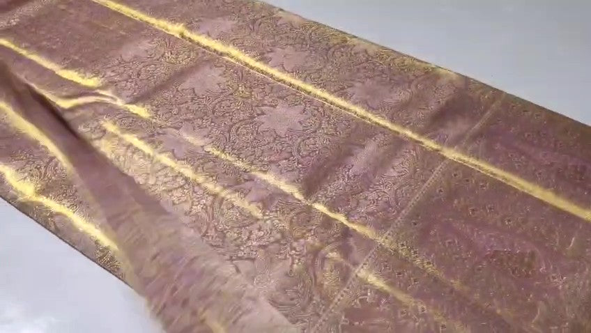 Neatly folded baby pink Kanchipuram handloom tissue silk saree displaying the rich pallu and shimmering metallic finish.
