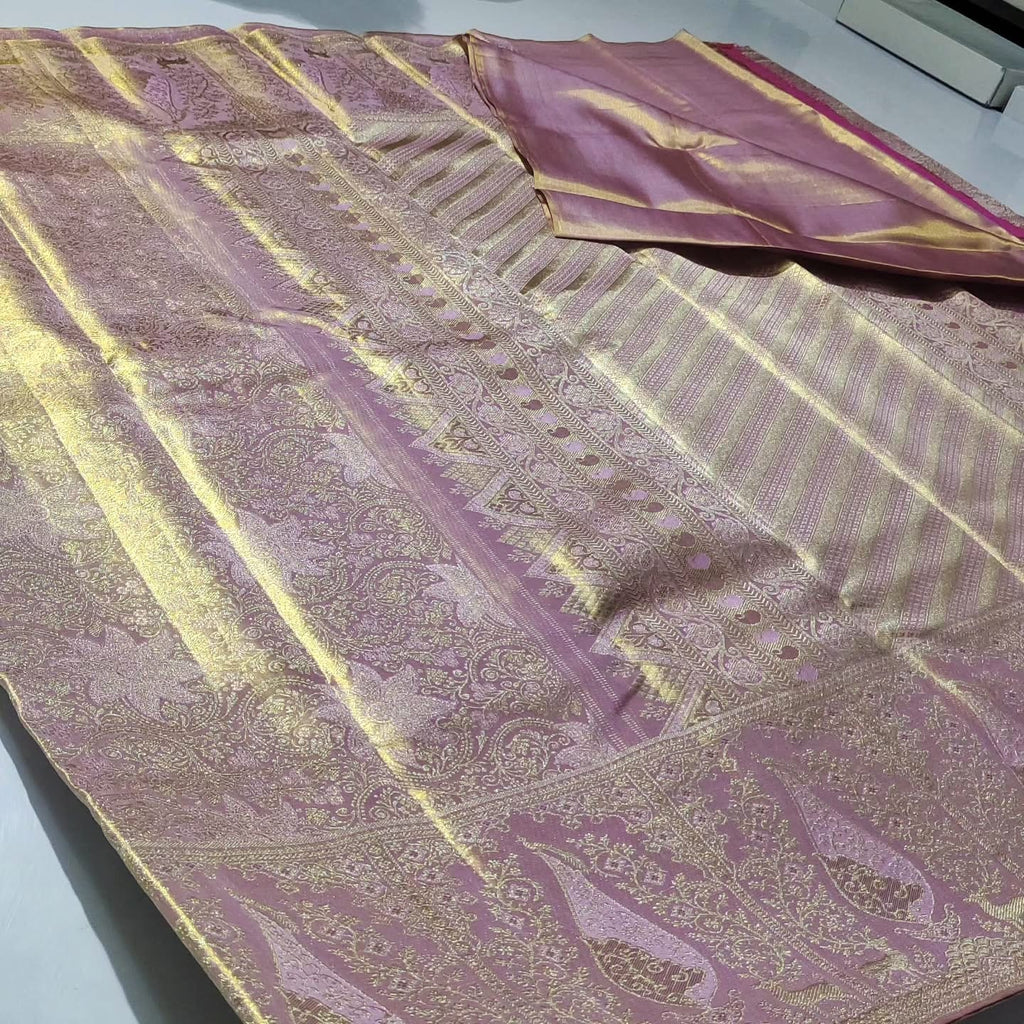 Neatly folded baby pink Kanchipuram handloom tissue silk saree displaying the rich pallu and shimmering metallic finish.